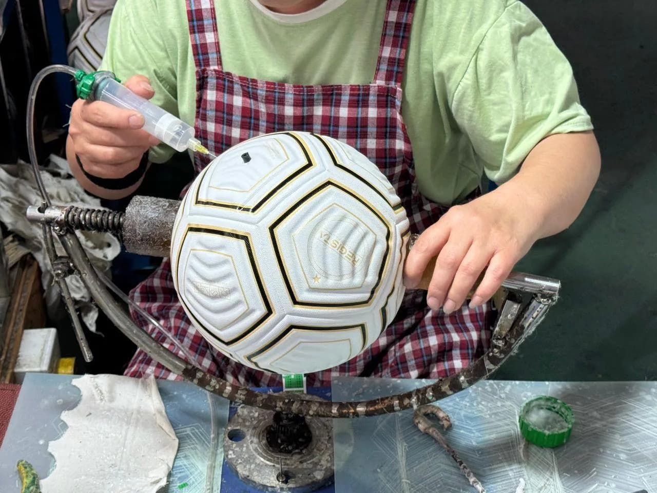 Factory technician working by hand on a white and gold football